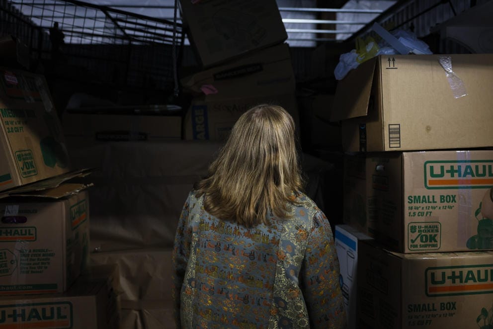 a woman looks into a storage unit filled with boxes
