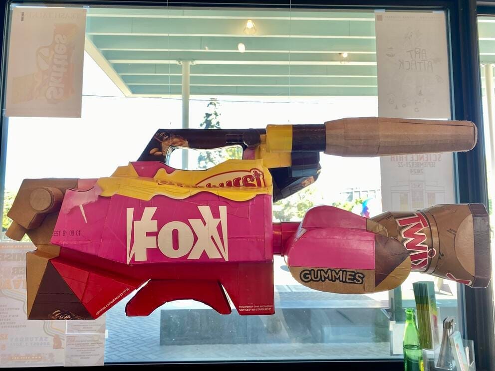 a hanging cardboard sculpture of a video camera made from candy cartons