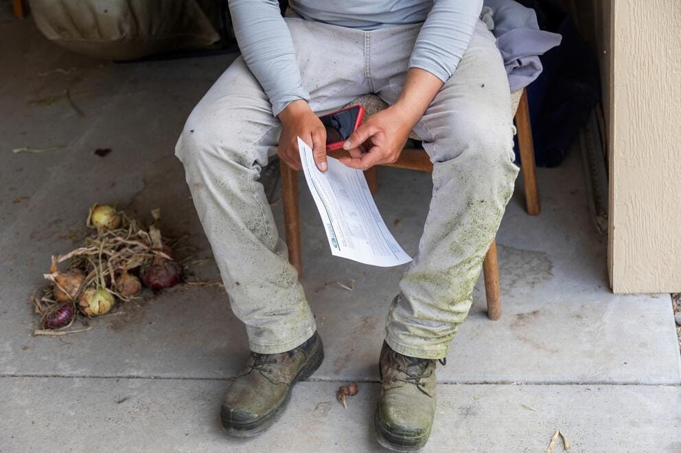 A seated person seen from the neck down holds a piece of paper.