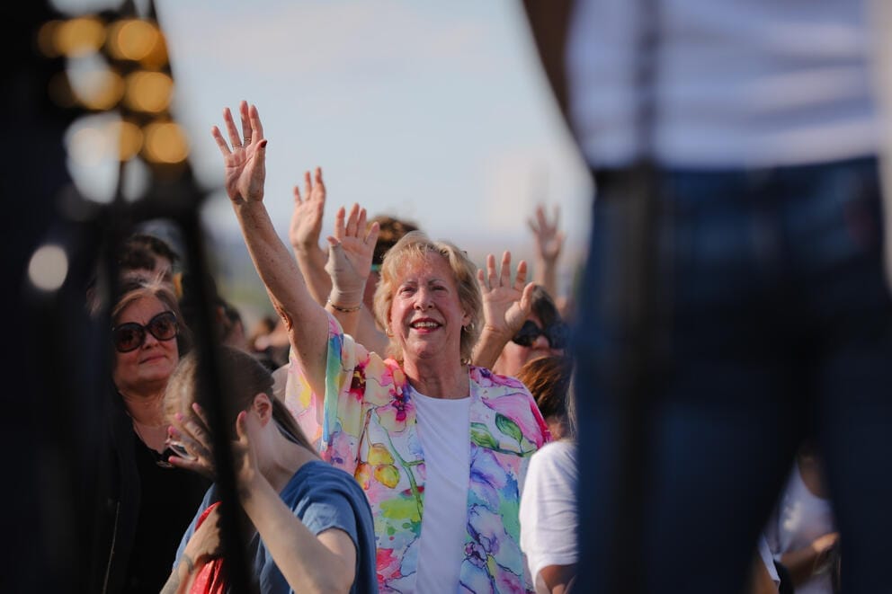Yakima Mayor Patricia Byers stands in the front row of a crowd with her arm raised