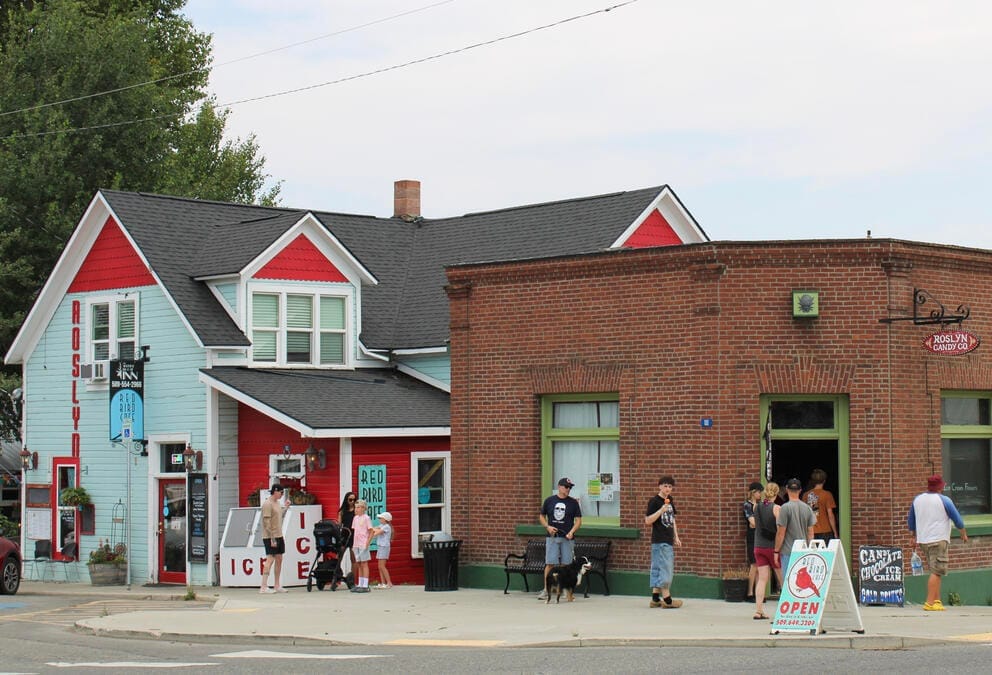 People are on sidewalks in front of brick buildings.