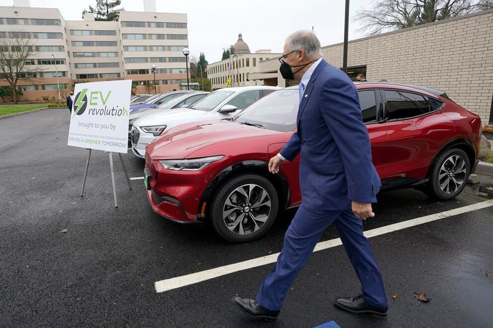 Washington Gov. Jay Inslee walks past a Ford Mustang Mach-E electric vehicle