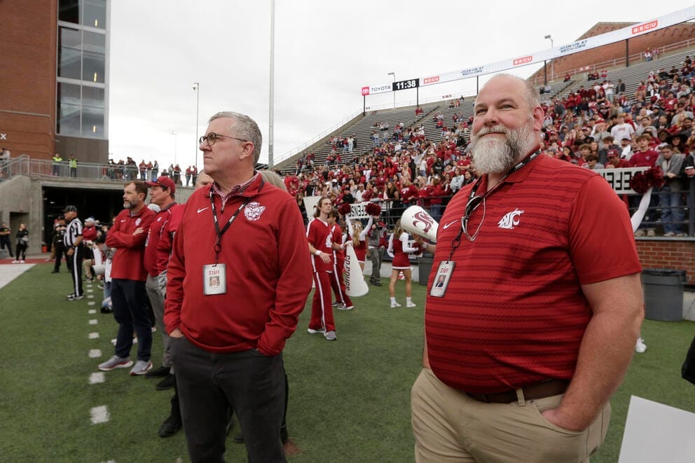 Schulz on the sidelines at a football game with a leader of the WSU foundation