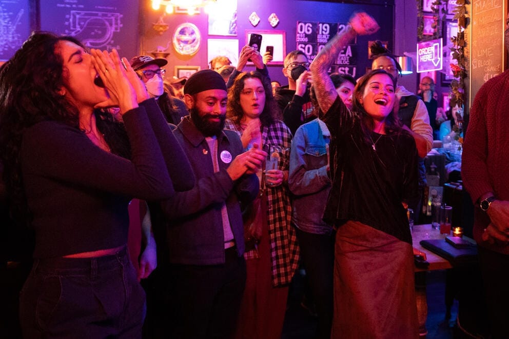 a crowd of supporters cheers in a bar