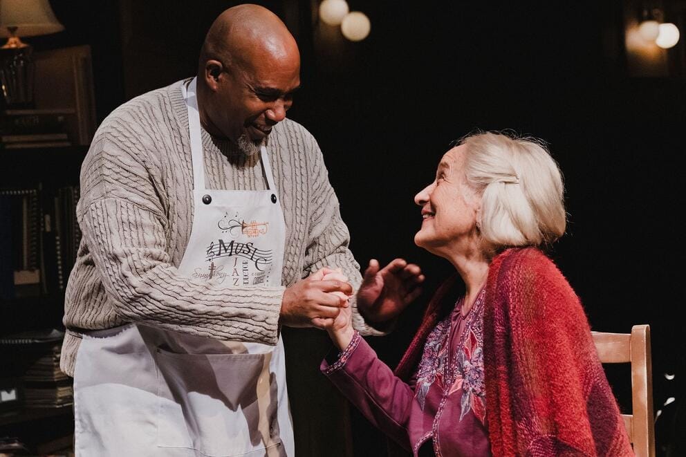 Two people clasp hands on stage