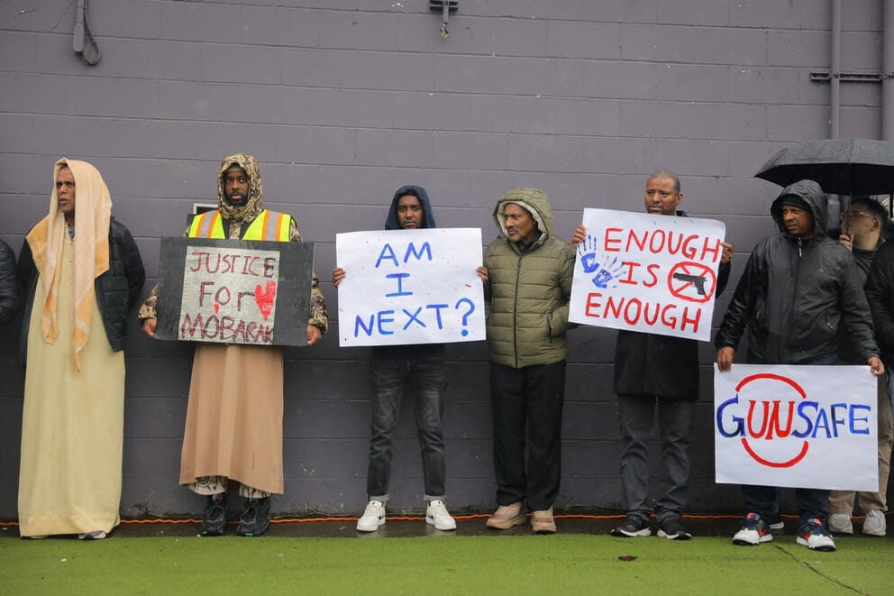 a group of people stand shoulder to shoulder holding signs