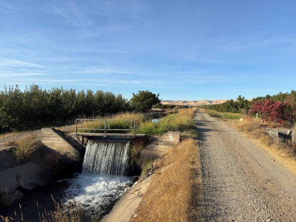 Water comes through a canal next to a gravel path.