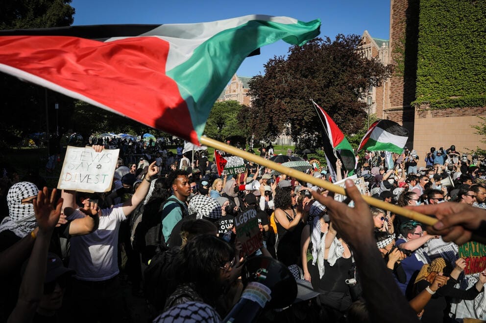 A large crowd on the University campus waves Palestinian flags and signs
