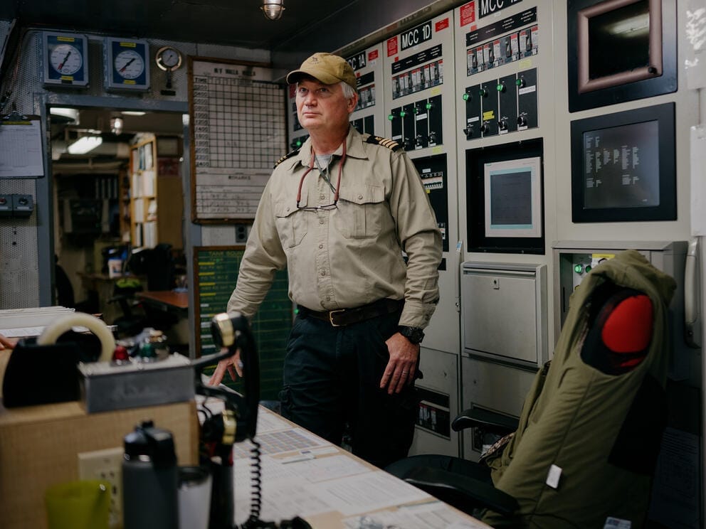 A portrait of Sean McManus standing behind a desk in the engine room of a ferry