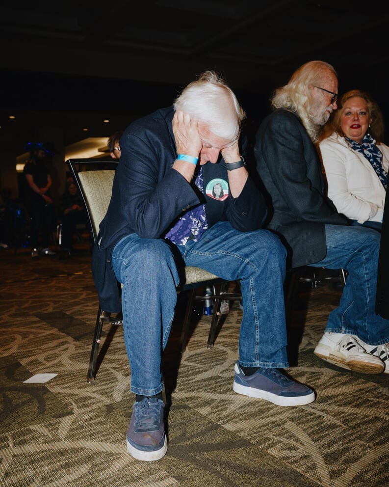 A man sitting on a chair holds his head in his hands
