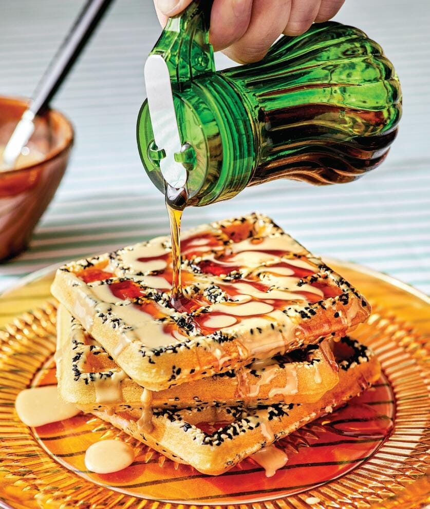 syrup being poured onto a stack of waffles