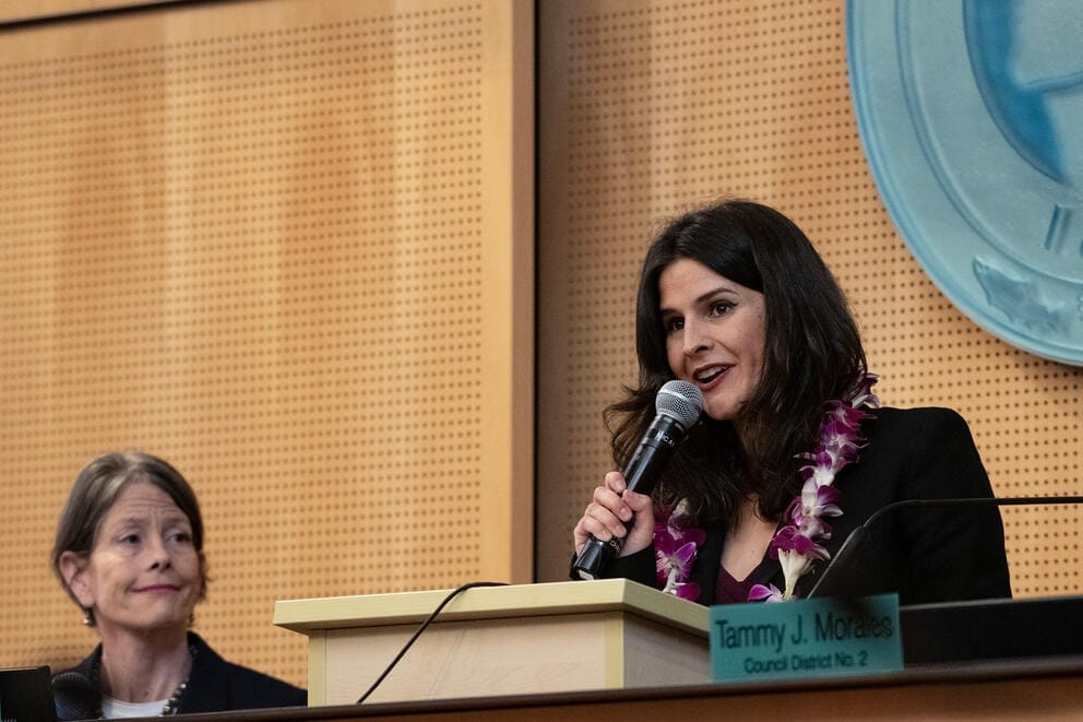 Alexis Mercedes Rinck stands on the Seattle City Council dias and gives a speech into a micr