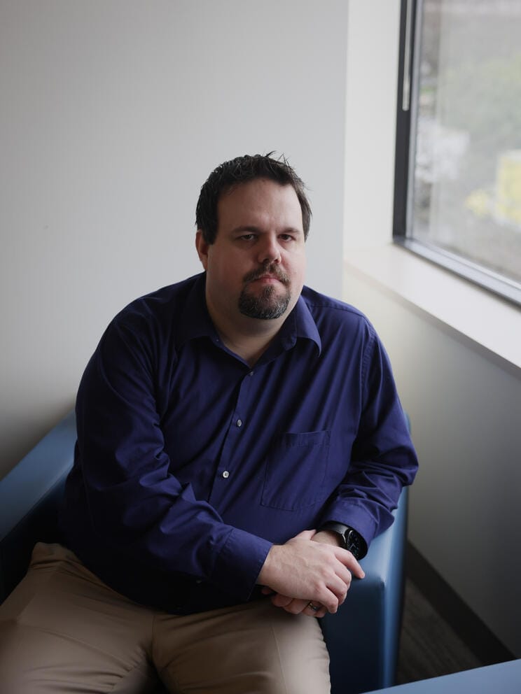 a vertical portrait of Andy Sampson sitting near a window