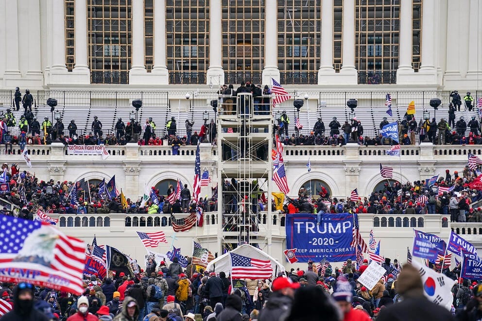 A large number of people crowd the steps and windows outside of the U.S. Capitol building.