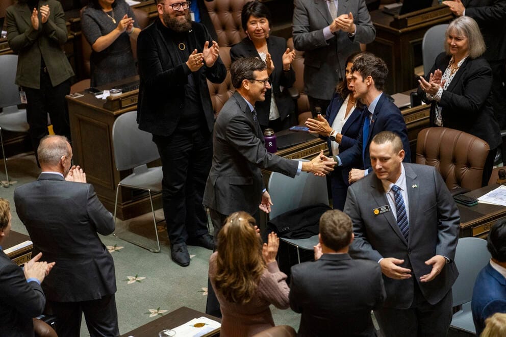 Bob Ferguson shakes hands with a legislator as others stand and applaud