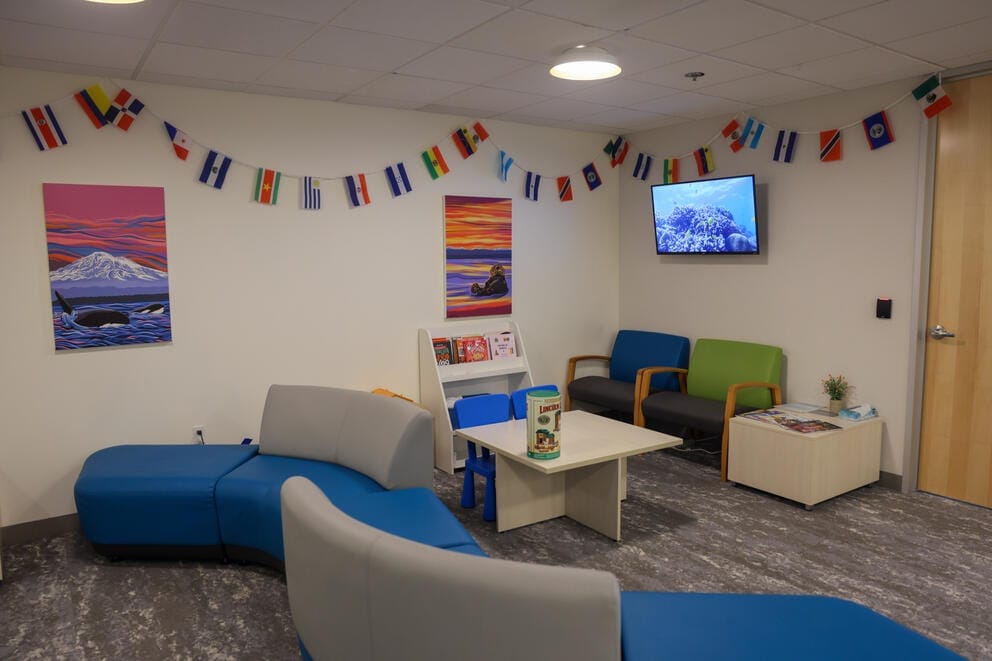 A waiting room with couches and colorful paintings on the wall