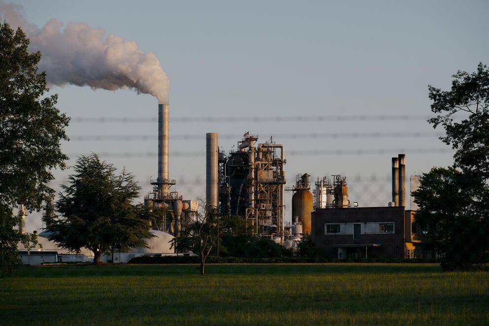 Smoke comes out of a chimney at an oil refinery