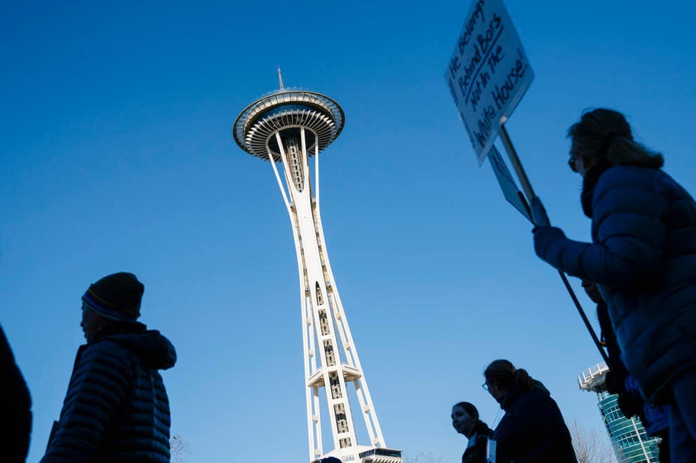 marchers walk past the space needle in seattle