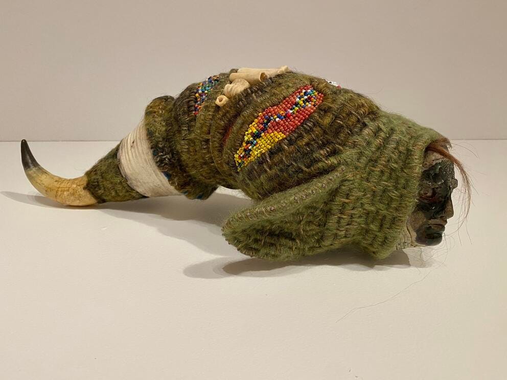 a textural, fishlike sculpture including a tail made of bone, a woven fiber body and a glass face