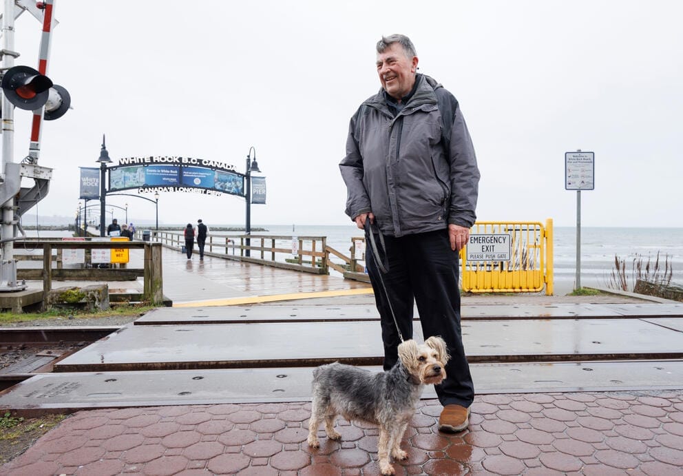 A person with a dog on a wet concrete pier.