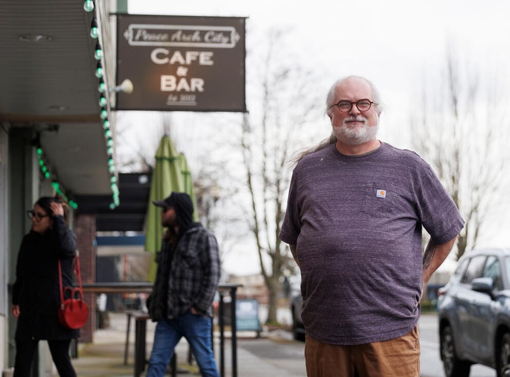 A person stands in front of a blurry sign that says
