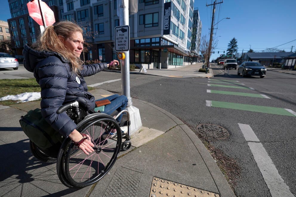 a woman in a wheelchair waits to cross the street in seattle