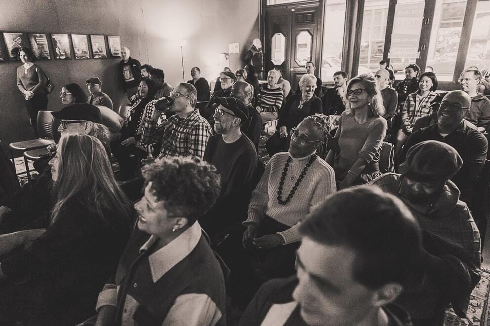 black and white photo of people listening to jazz in windowed room