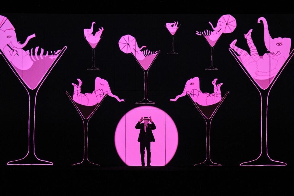 cartoon image of pink elephants in martini glasses with a real singer in front