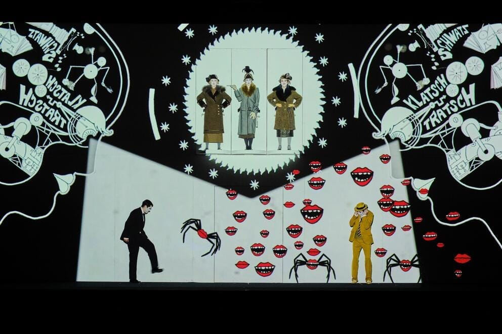 a cartoonish backdrop with disembodied smiles and actors standing in front