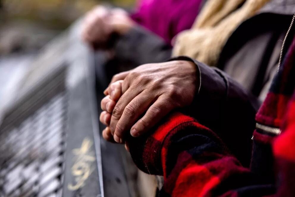 Three pairs of hands hold each other on a railing