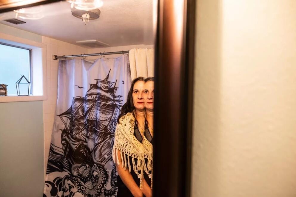A person looks at their reflection in a bathroom mirror