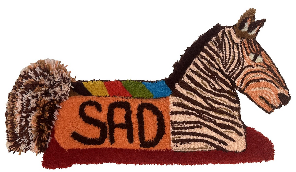 a tufted rug in the shape of a zebra with a saddle that says SAD