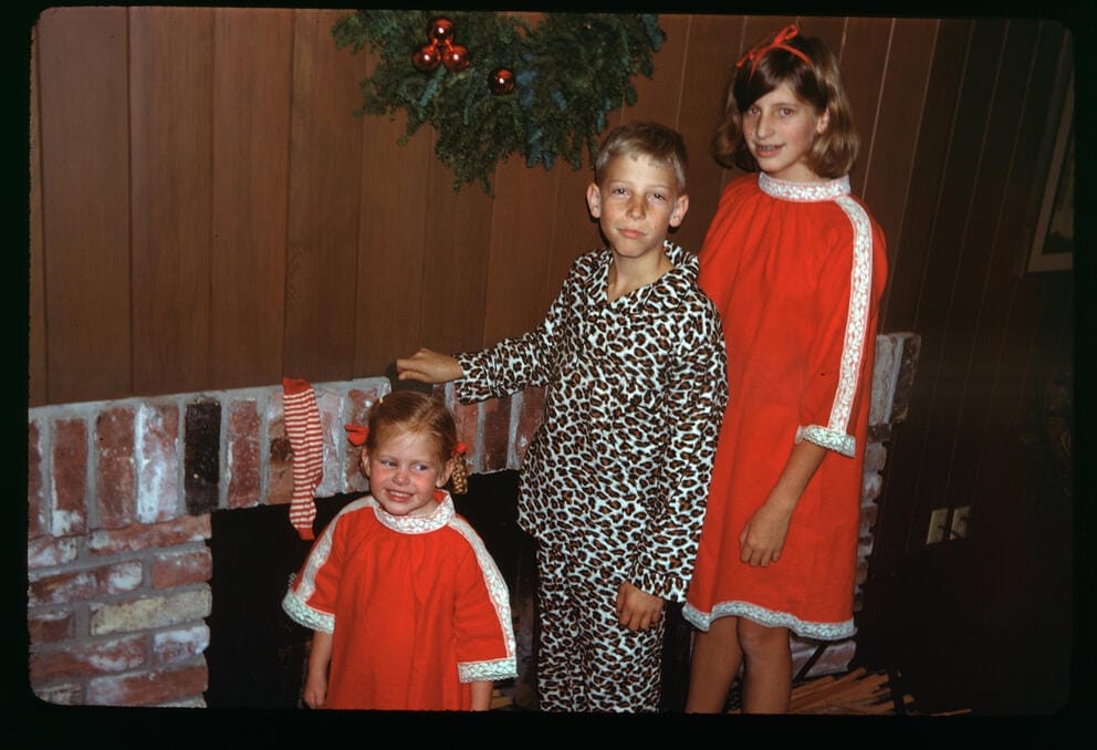 three children pose in front of a wreath