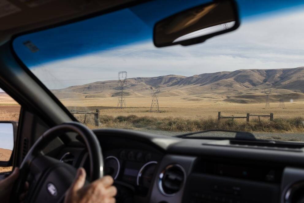 view of power lines and wheat fields out the front windshield of a truck