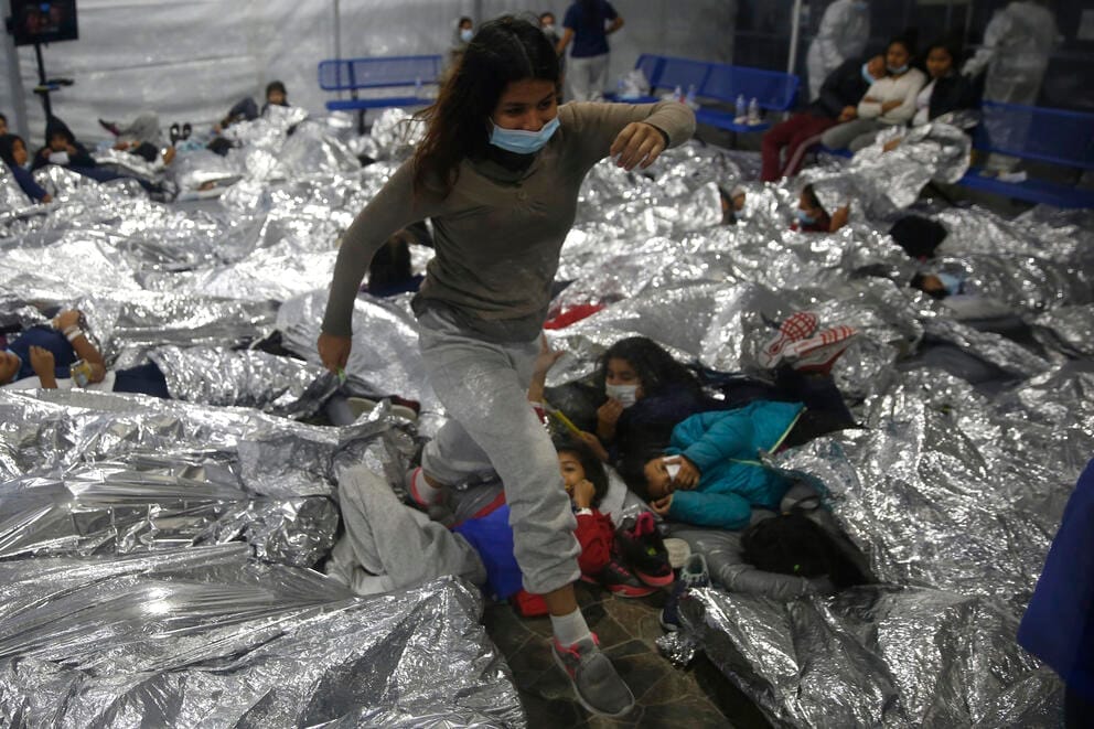 Young people in masks lie down in close quarters under Mylar blankets.