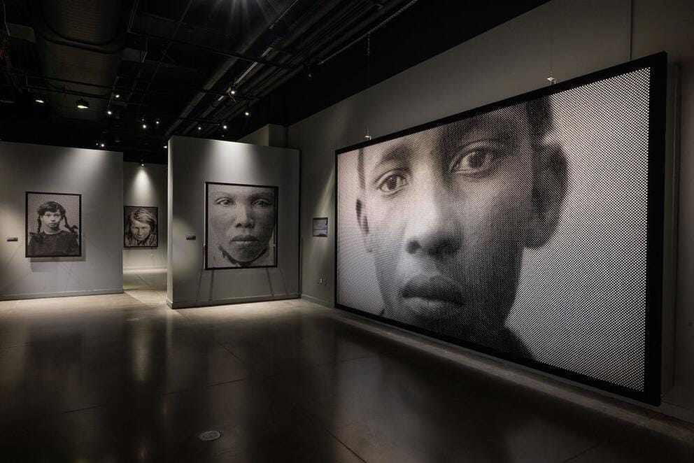 a gallery full of large scale black and white photos of human faces
