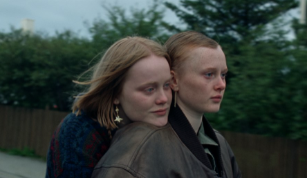 A young person puts their chin on another's shoulder in this film still