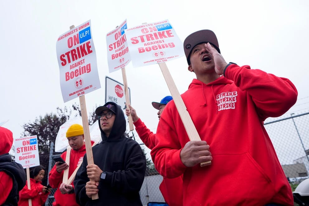 people stand holding signs and yelling during a strike at Boeing