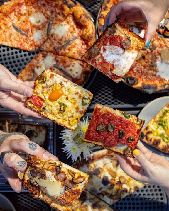 People holding square slices of pizza