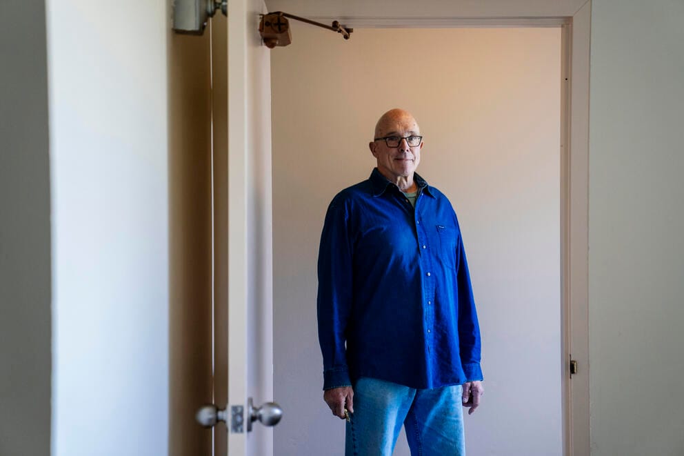 A man stands in a doorway of an apartment building.