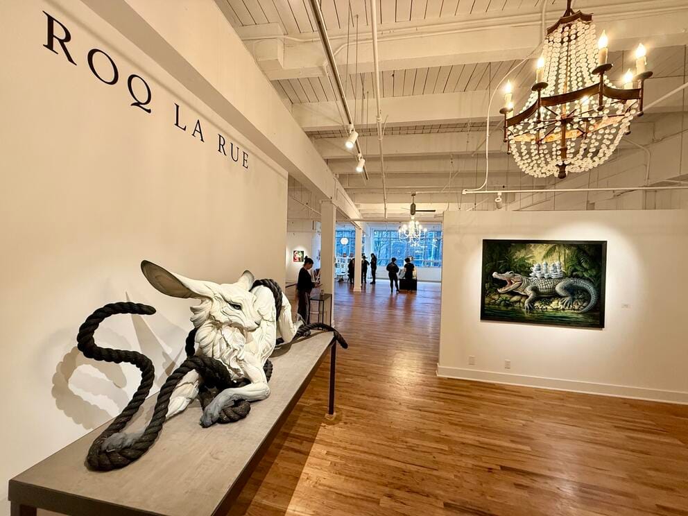 a gallery entrance in an older building with wood floors and high ceilings and a large rabbit sculpture on a table
