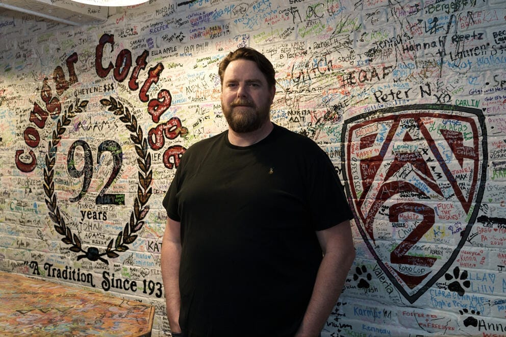 a man stands in front of a wall with writing all over it from WSU football fans