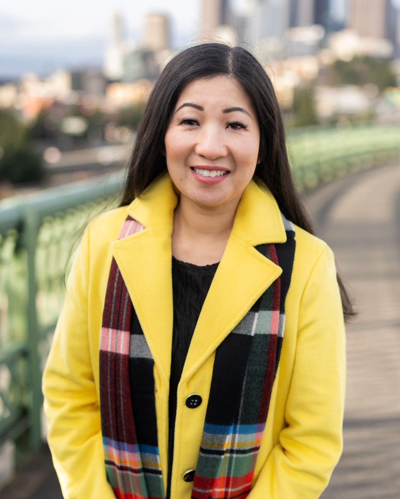 a portrait of tanya woo standing on a bridge looking out over seattle