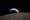 A deep-space NASA photo of the pocked surface of the moon, behind which Earth is setting like the sun.