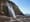 Photograph of a waterfall on a coastline, in which a person is hidden in a camouflaged costume.