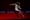 A woman dancing on a dark stage wearing a skimpy slip kicks her leg up, splashing water. 