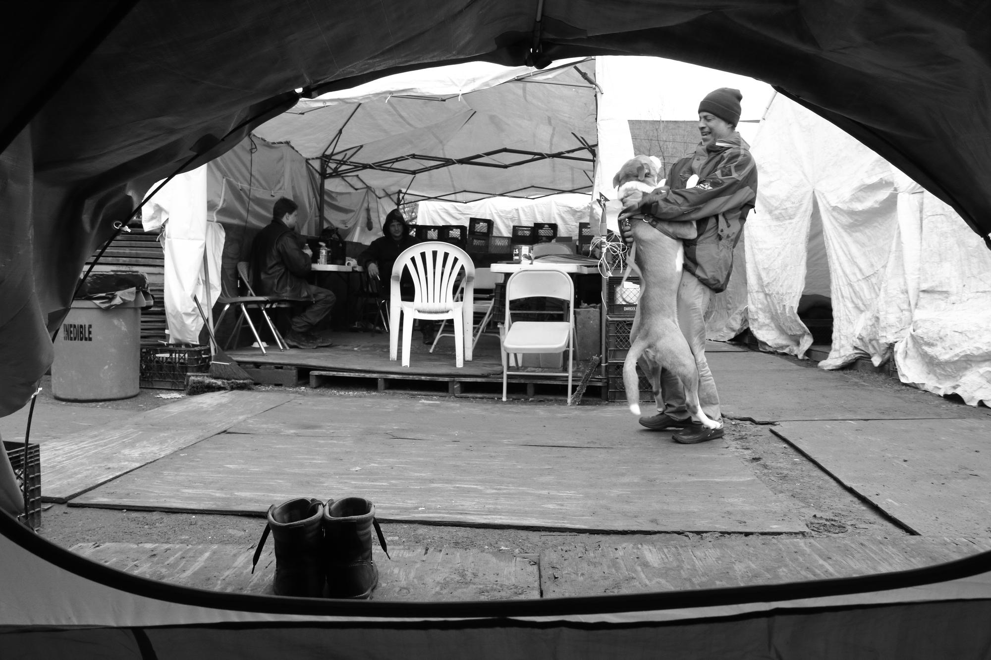 Houdini, a dog owned by encampment resident Sonny, plays with another resident, Ali, at Tent City 3 in Seattle's Central District during March 2018. (Gemina Garland-Lewis)