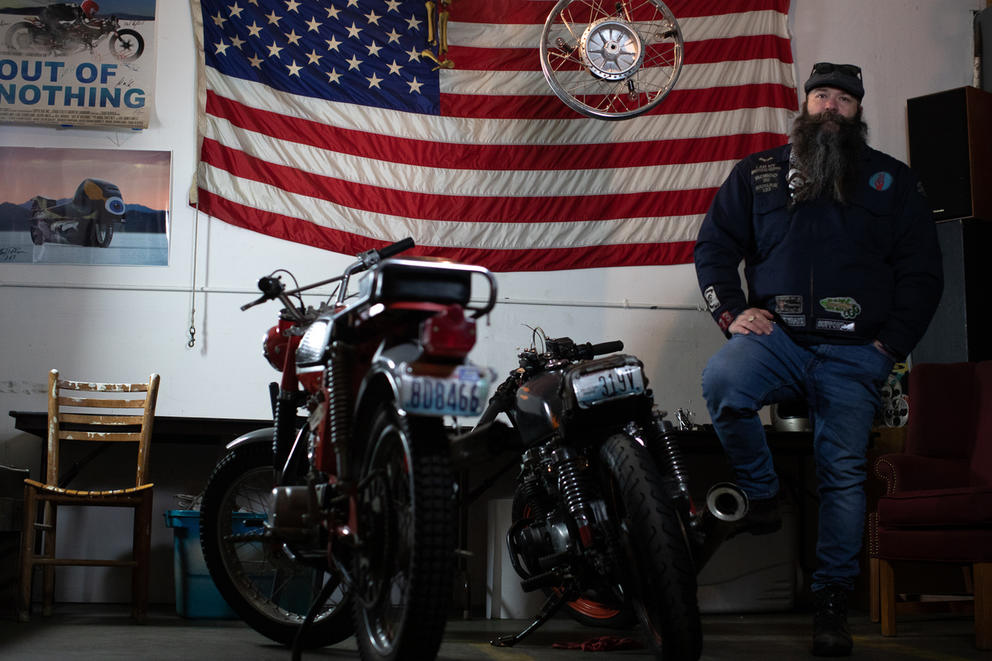 Ziehe sits next to bikes with flag behind him.