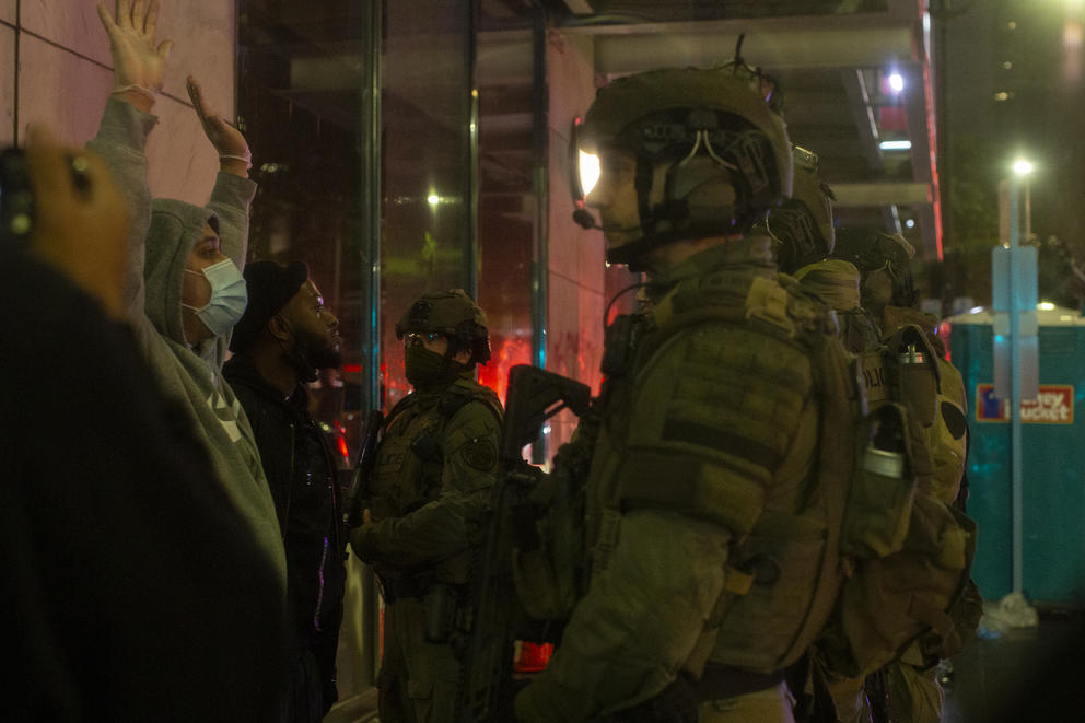 Police talk to a demonstrator who has their arms up 