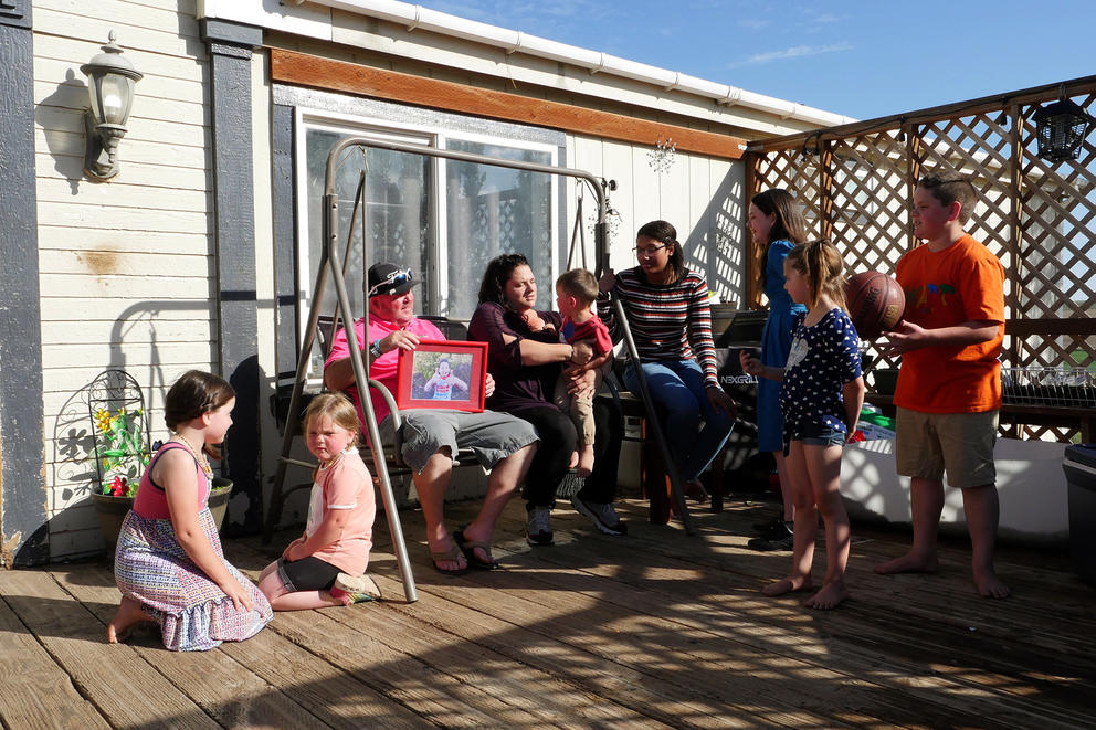 Two parents sit in a porch swing surrounded by seven children